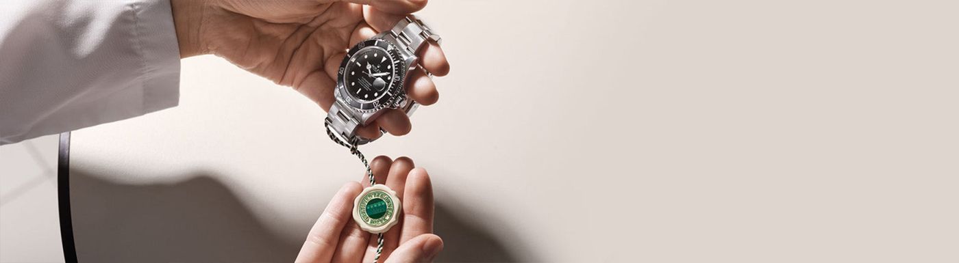 A pre-owned Rolex Submariner held alongside its green Rolex Certified Pre-Owned wax seal